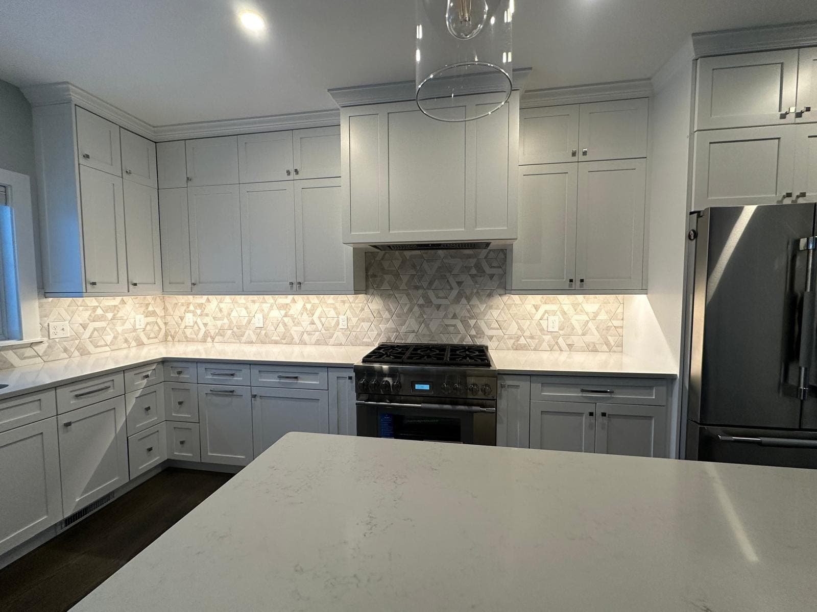 PizTile kitchen with white cabinetry, geometric tile backsplash and quartz counters