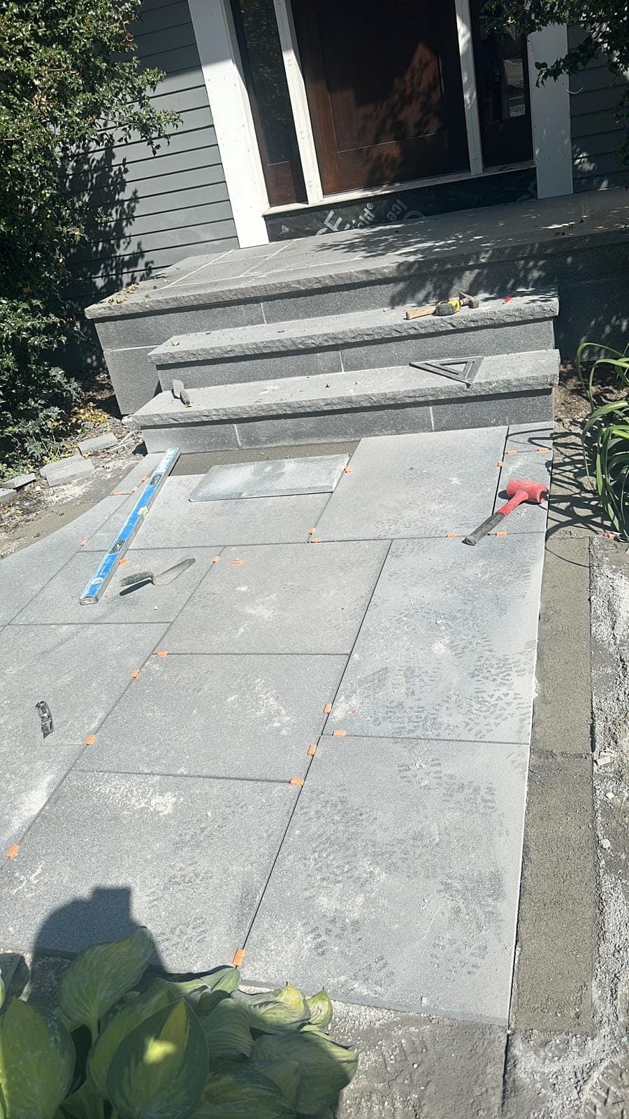 Bluestone patio being set to line with spacers and a level over a prepared base