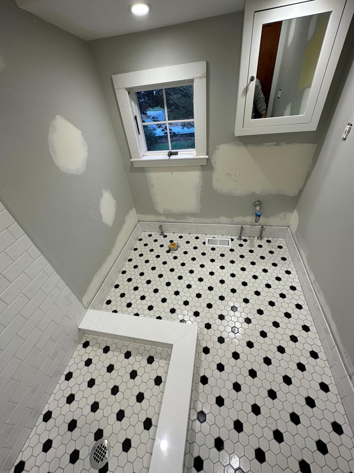 White hexagon mosaic floor with a black accent pattern running true to a crisply tiled curb